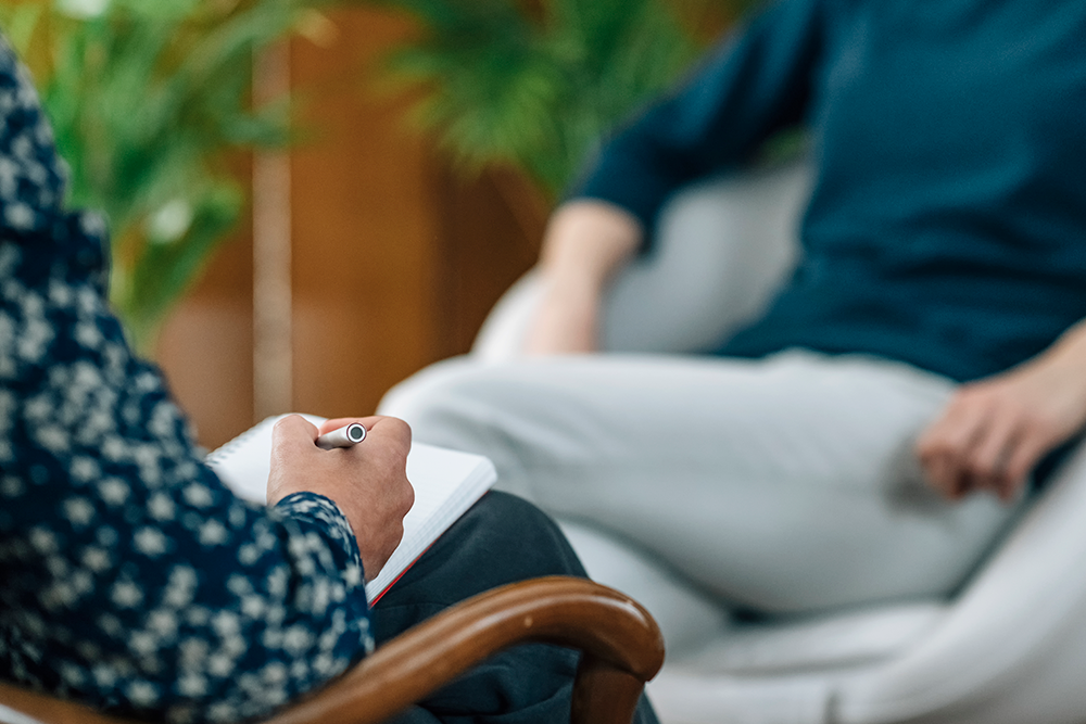 Therapist writing on a notepad in a session